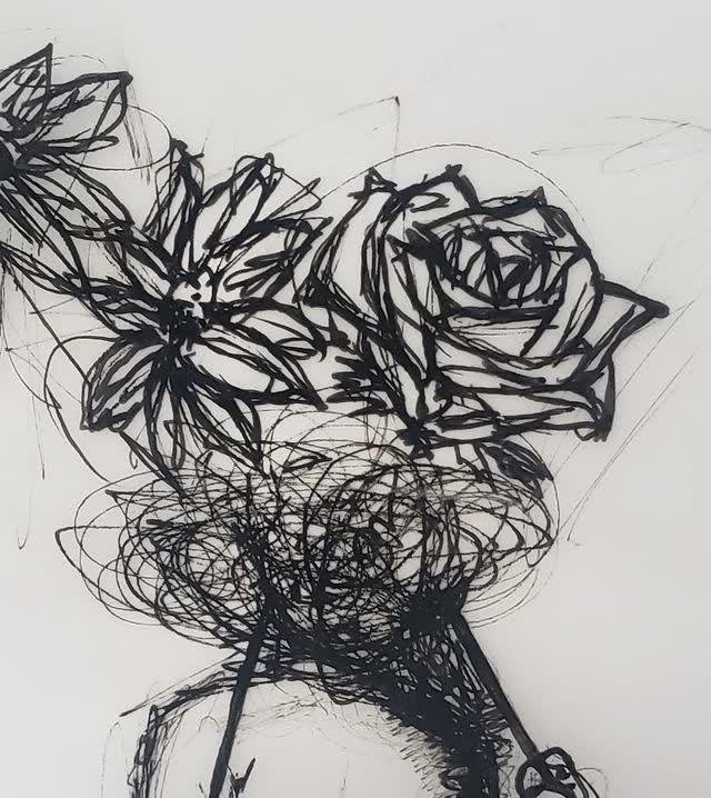 Pen sketch of flowers — a rose and a daisy-like bloom with scribbled stems and leaves — in loose black gestural lines on white paper.